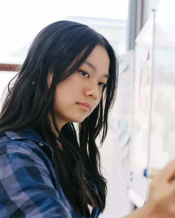 Young girl in blue shirt writing with a marker